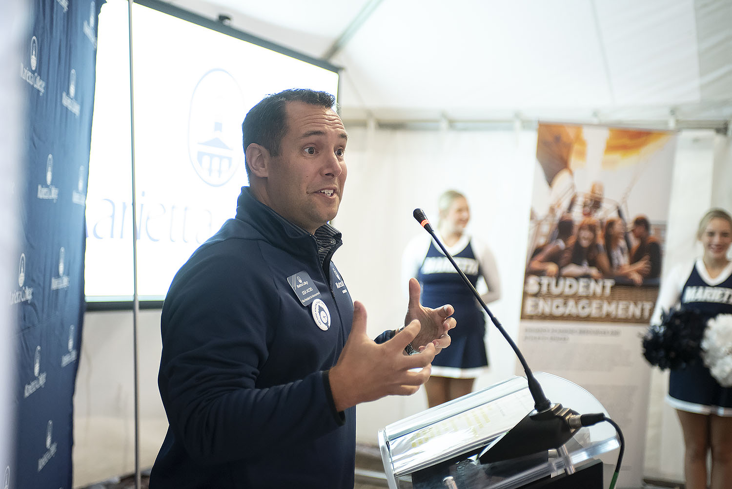 Josh Jacobs speaks under the tent at the All Alumni and Friends event