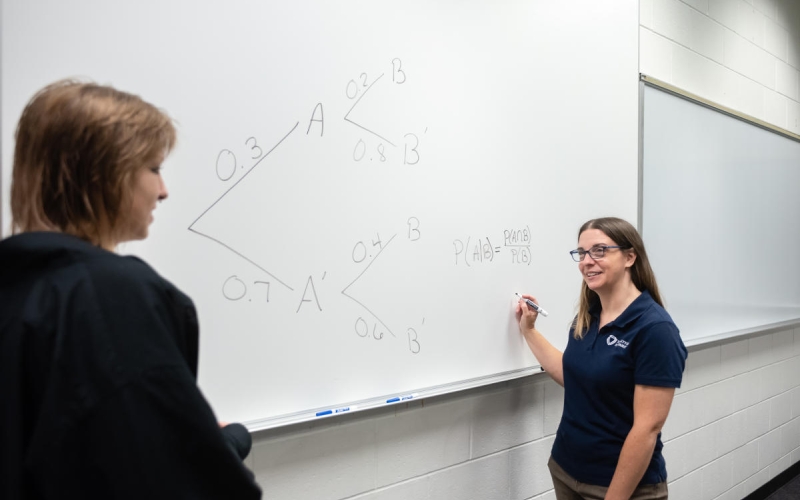 Marietta College professor Holly Menzel talks to a student in front of a white board