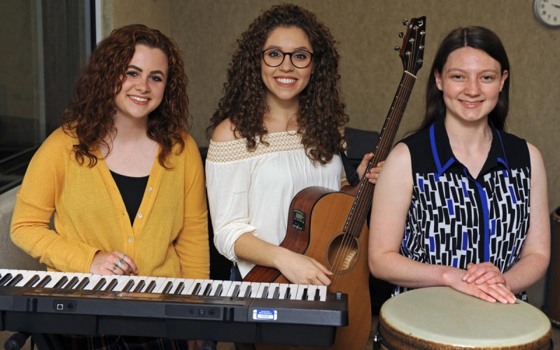2021 graduates Hannah Miller, Lauren Eakle and Sadie Johnson stand with three instruments