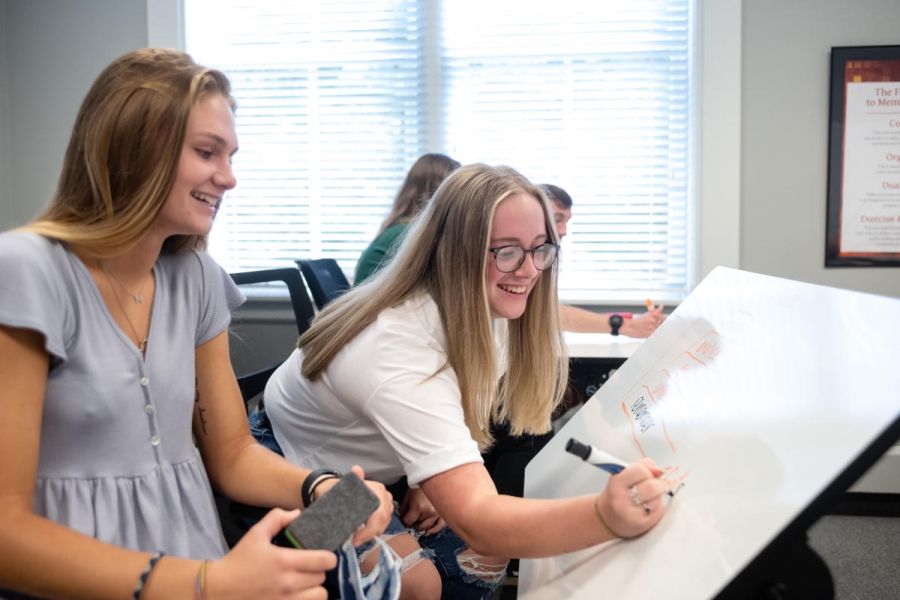 Two Marietta College education students write on a whiteboard